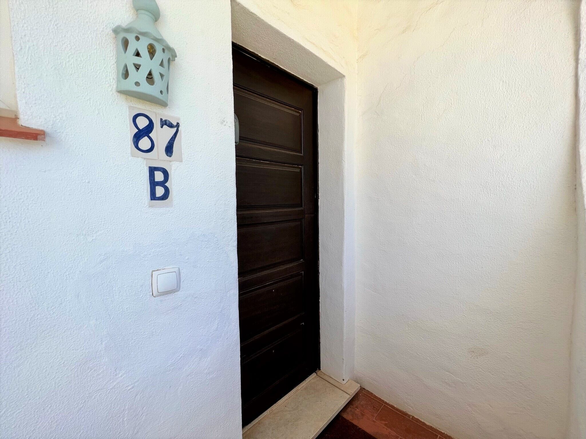 A white wall with the numbers "87 B" and a door.
