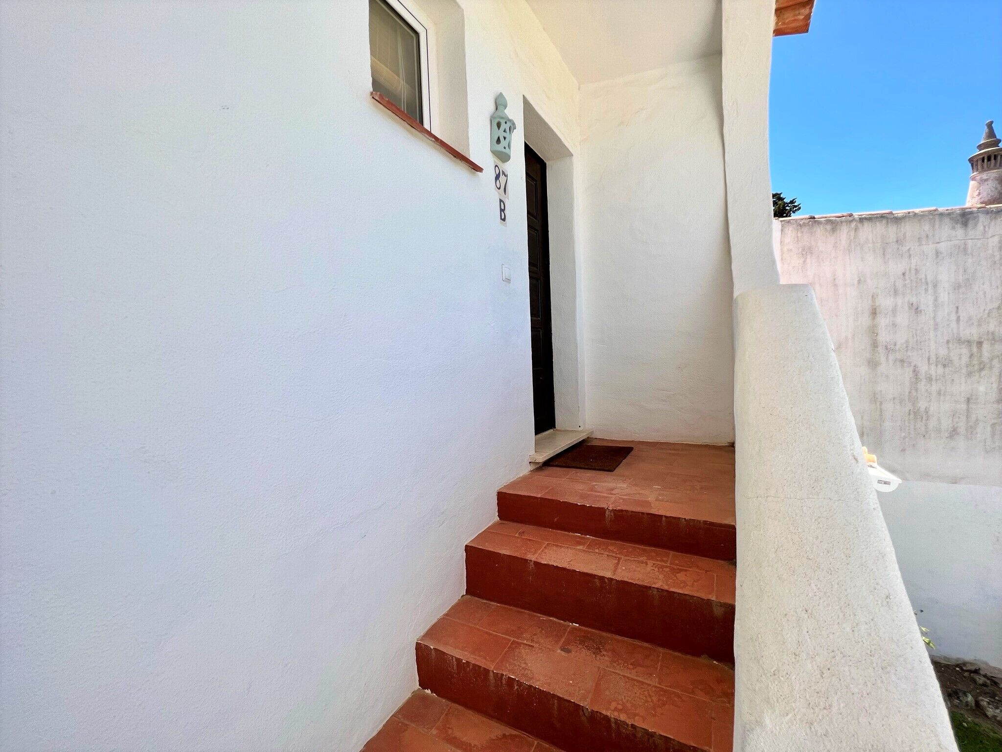 Un escalier étroit menant à une porte surmontée d’une petite fenêtre.