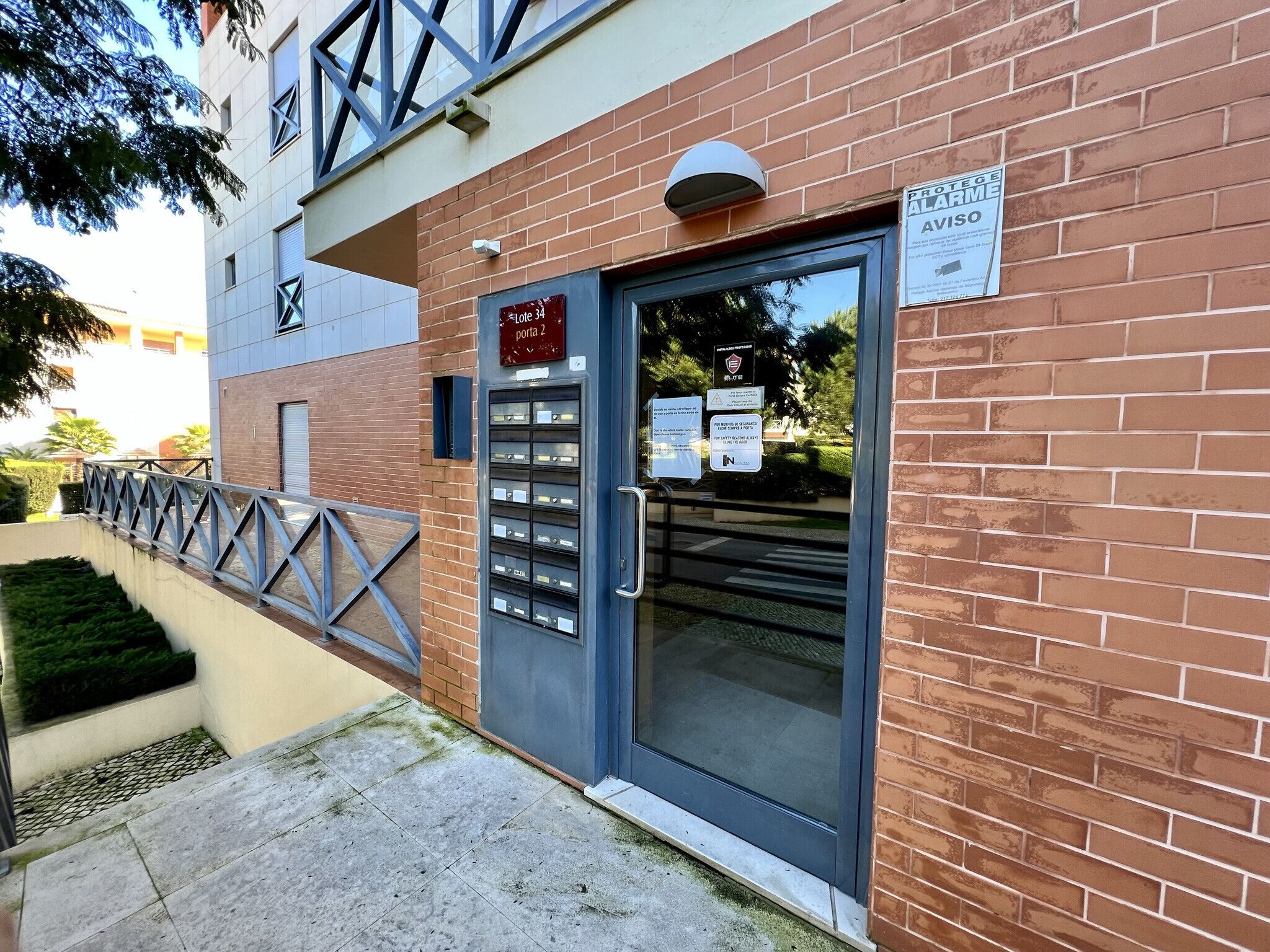 Ein Gebäude mit Backsteinfassade, einem Metallgitter und einer Tür, an der ein Schild mit der Aufschrift 'Porta 2' angebracht ist.