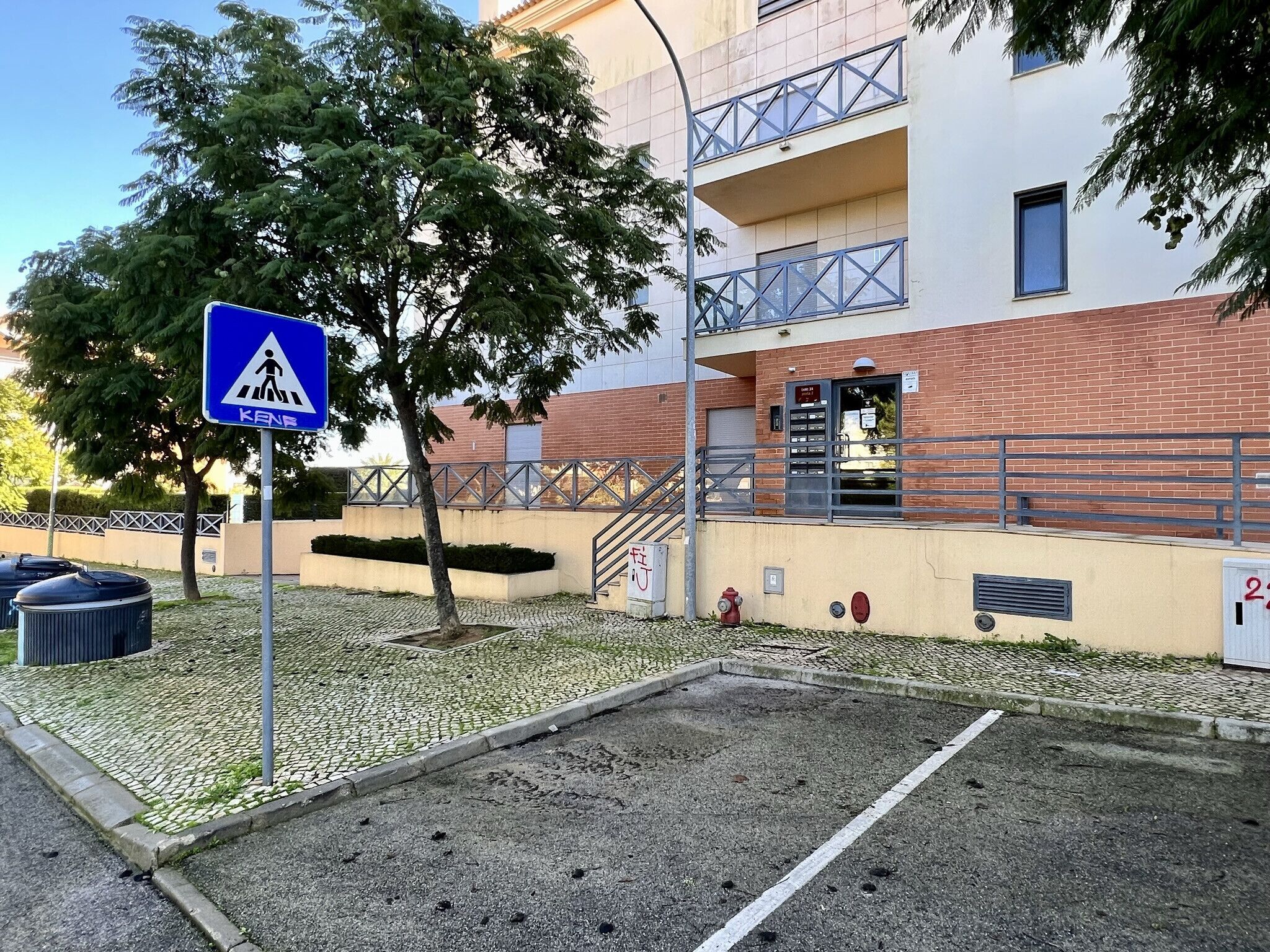 Een voetgangersoversteekplaats, een gebouw met een bakstenen gevel en een trap naar een ingang.