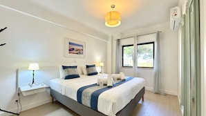 A modern hotel room with a large bed, bedside tables, a ceiling light, and a window with curtains. - Albufeira Cosy by Homing (Albufeira)