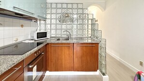 A compact kitchen with wooden cabinets, a microwave, and a sink. - Albufeira Cosy by Homing (Albufeira)