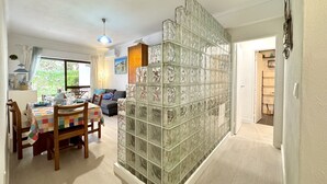 A dining area with a table set for two, a sofa, and a decorative glass partition. - Albufeira Cosy by Homing (Albufeira)