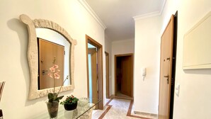 A hallway with a glass display case, a mirror, and a door leading to another room. - Vilamoura Typical 2 With Pool by Homing (Loulé)