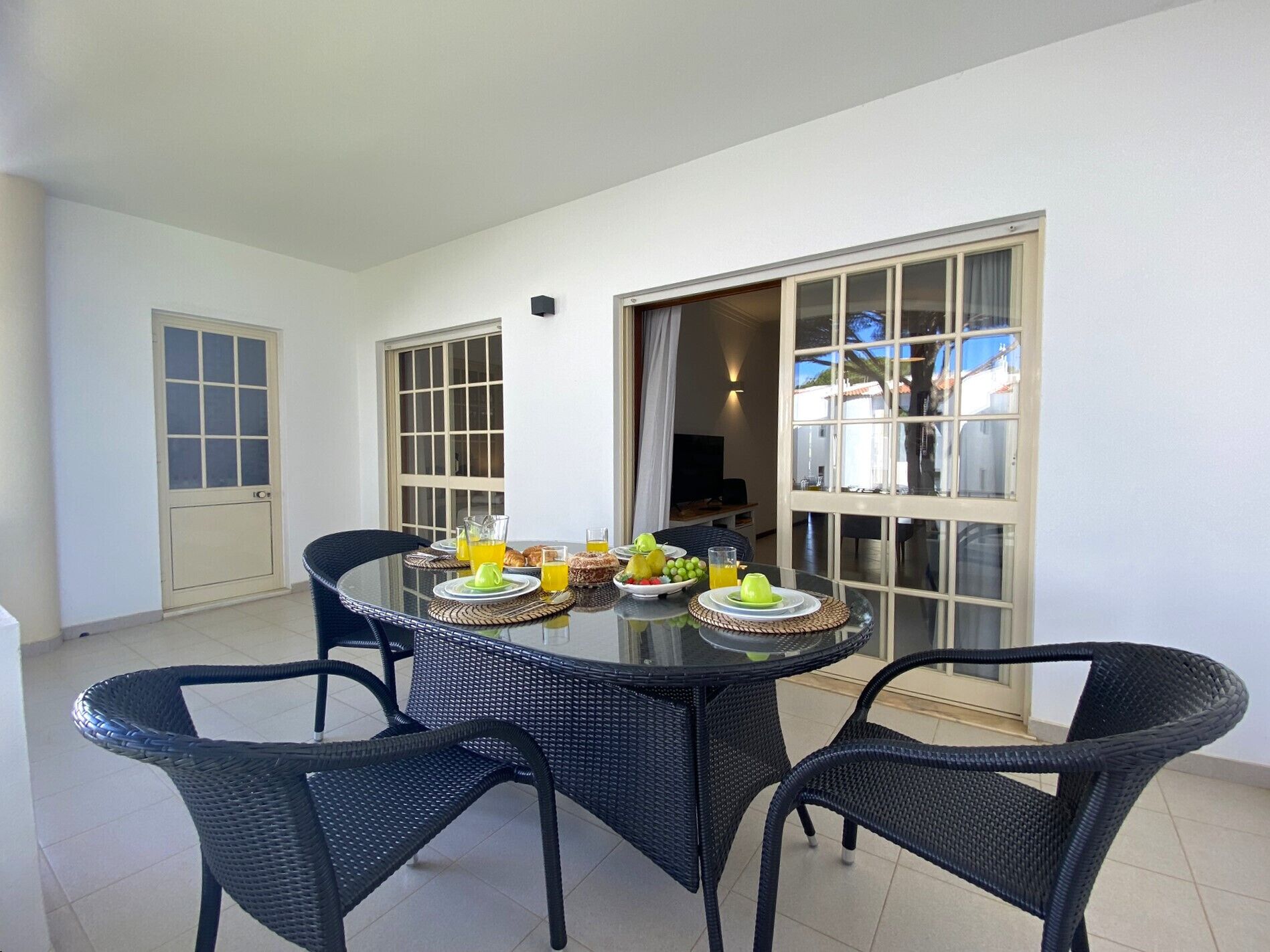 Un comedor con una mesa redonda y cuatro sillas, una puerta y una ventana con cortinas.