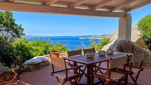 Un conjunto de mesa y sillas de madera al aire libre, con vista al mar.