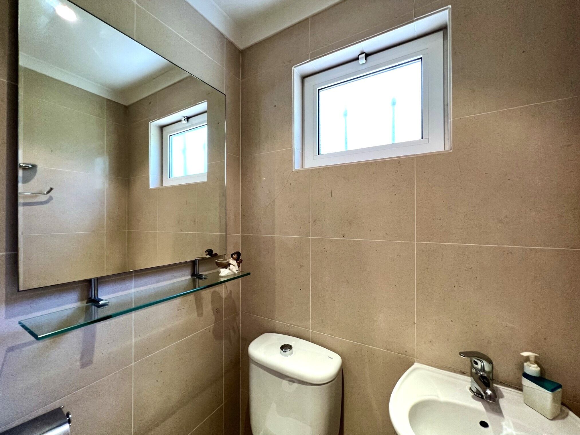 A bathroom with a toilet, sink, and a mirror.