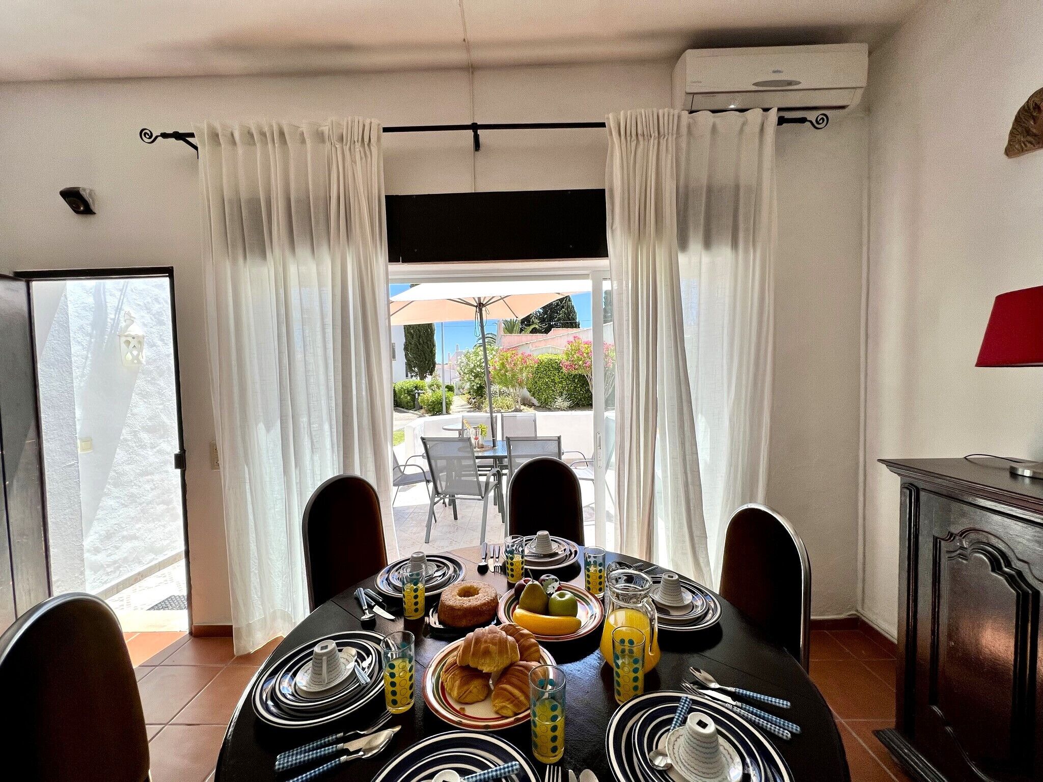Un comedor con una mesa dispuesta para el desayuno, que incluye cruasanes, fruta y jugo.