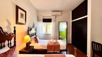 Habitación de hotel con dos camas, una ventana con cortinas, un equipo de aire acondicionado y vistas al exterior.