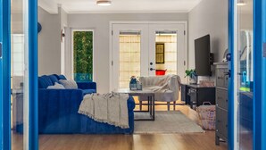 Een moderne woonkamer met een blauwe zithoek, een salontafel en een televisie.