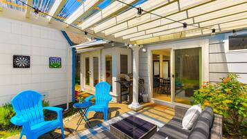 A covered patio with blue chairs, a sofa, and a dining table.