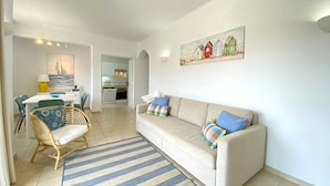 A living room with a sofa, a dining table, and a kitchen in the background. - Vilamoura Twins 1 With Pool by Homing (Loulé)