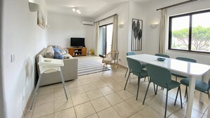 A modern living room with a sofa, TV, dining table, and chairs. - Vilamoura Twins 1 With Pool by Homing (Loulé)