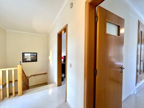 A hallway with a wooden door, a staircase, and a framed picture on the wall. - Pêra Brightness Villa by Homing (Silves)