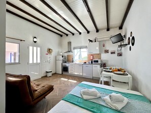 Ein modernes Zimmer mit Bett, einer braunen Ledersofa, einer Küchenzeile und einem Essbereich.