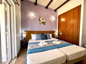Ein Schlafzimmer mit einem Holzkopfteil, zwei Nachttischen mit Lampen, einem großen Bett mit vielen Kissen und einem Holzschrank.