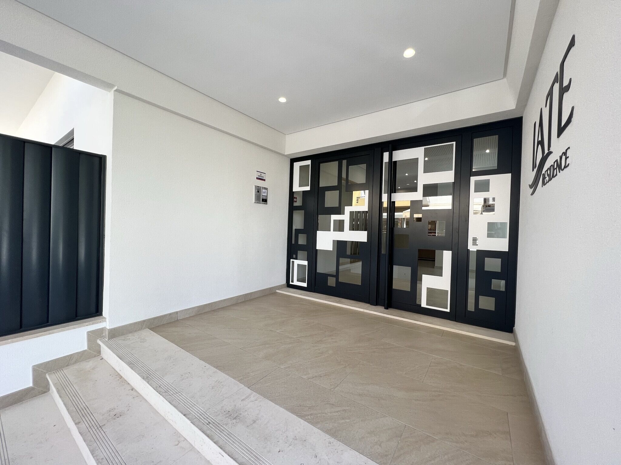 A modern hotel entrance with a staircase leading to the upper floor.