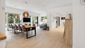A modern interior with a dining area, a TV mounted on the wall, and a wooden cabinet. - Lovely home in Ebeltoft with sauna (Ebeltoft)