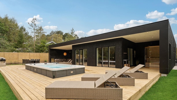 A modern outdoor deck with a hot tub, lounge chairs, and a covered seating area. - Lovely home in Ebeltoft with sauna (Ebeltoft)