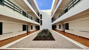 A modern building with a central courtyard, multiple balconies, and a clear sky. - Vilamoura Central 4 With Pool by Homing (Loulé)
