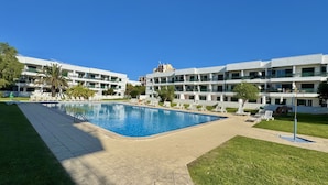 A hotel with a swimming pool surrounded by lounge chairs and palm trees. - Vilamoura Central 4 With Pool by Homing (Loulé)