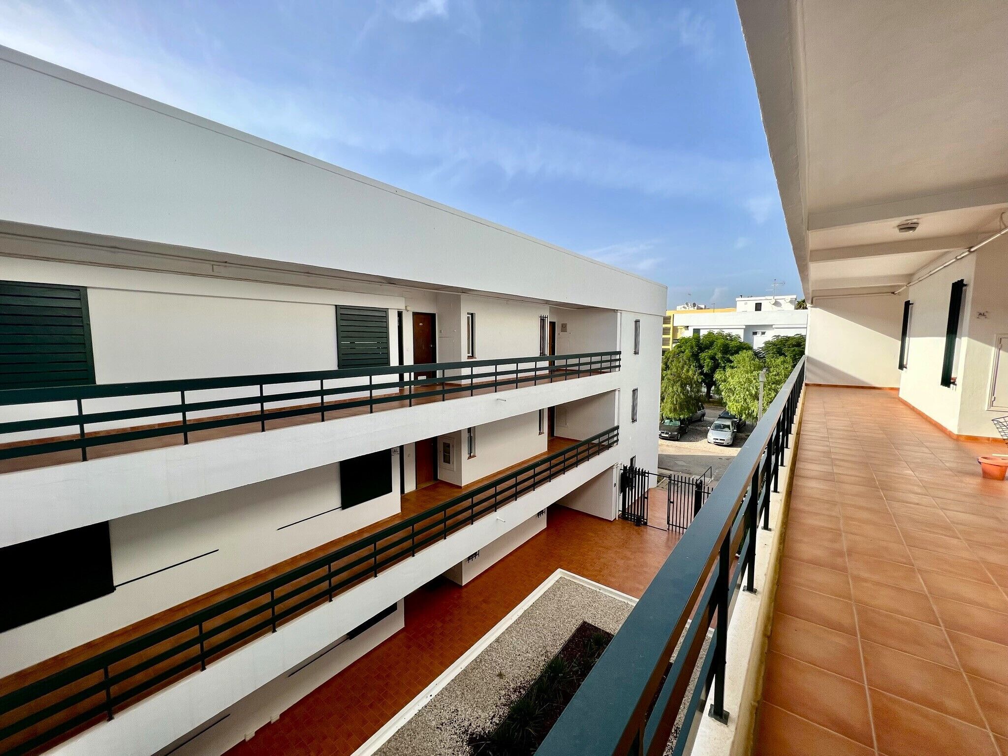Un edificio residencial de varios niveles con balcones y piso de baldosas.