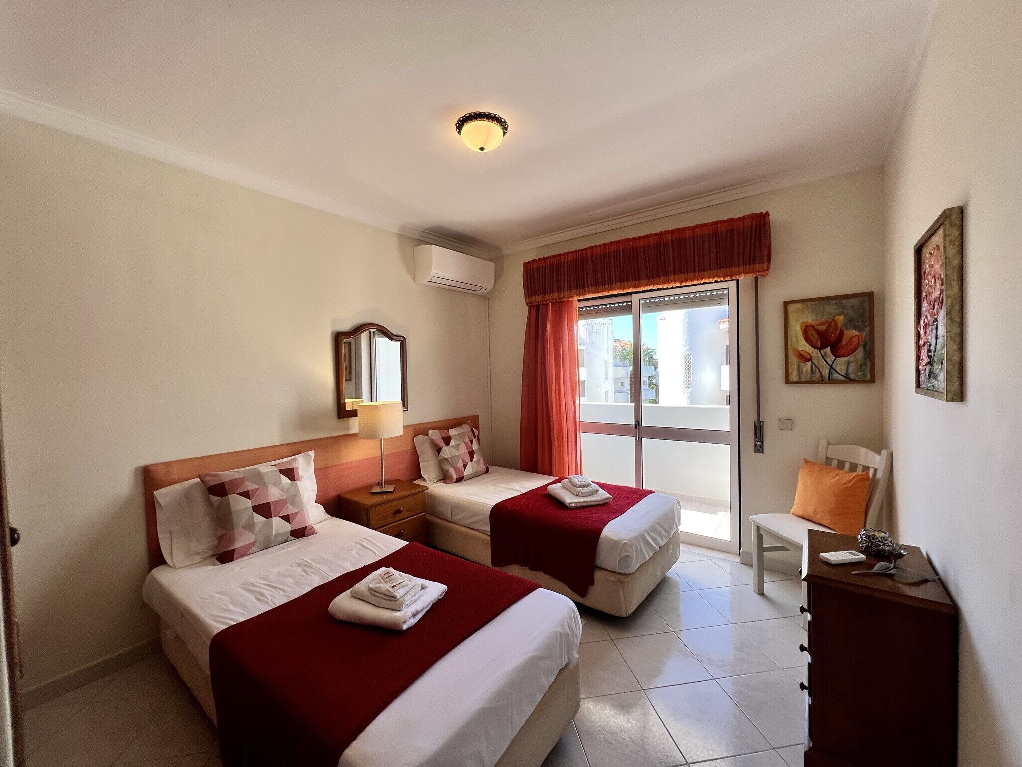 Habitació d'hotel amb dos llits, un escriptori, una cadira i una finestra amb vista.