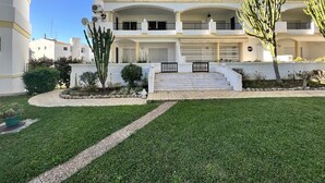 A multi-story building with a central staircase, surrounded by well-maintained lawns and cacti. - Vilamoura Garden View 1 With Pool (Loulé)