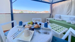 A covered outdoor dining area with a table set for two, featuring a pitcher, cups, and pastries. - Albufeira SKY Light With Pool by Homing (Albufeira)