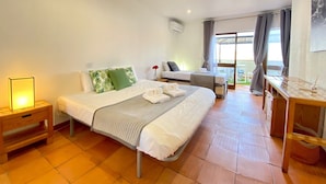 A hotel room with a large bed, a smaller bed, a desk, and a balcony with curtains. - Albufeira SKY Light With Pool by Homing (Albufeira)
