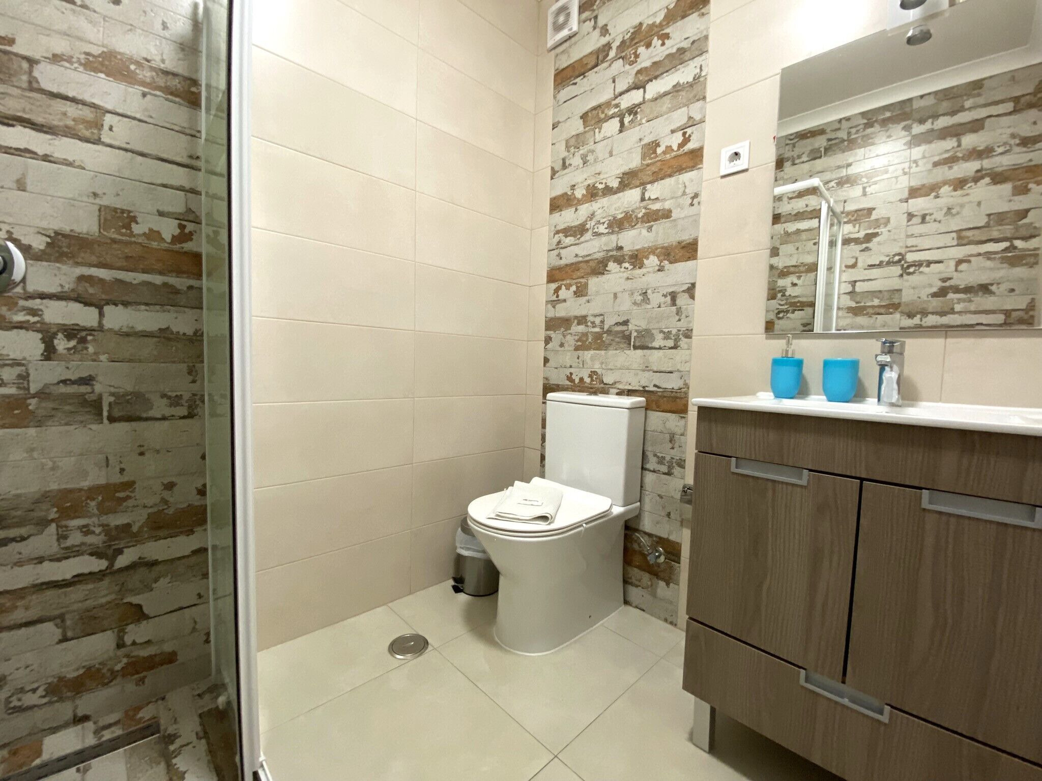 A bathroom with a toilet, a shower, and a sink with a mirror.
