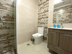 A bathroom with a toilet, a shower, and a sink with a mirror. - Quarteira Ocean Breeze 2 by Homing (Loulé)