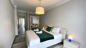 A modern hotel room with a large bed, a walk-in closet, and a hallway leading to another room. - Quarteira Ocean Breeze 2 by Homing (Loulé)