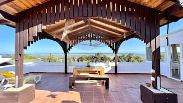 A covered outdoor area with a wooden pergola, a table, and chairs.