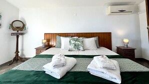 A hotel room with a wooden headboard, two bedside tables with lamps, a mirror, and two towels on the bed. - Tavira Vila Formosa 6 With Pool (Tavira)