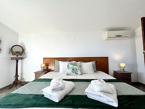A hotel room with a wooden headboard, two bedside tables with lamps, a mirror, and two towels on the bed. - Tavira Vila Formosa 6 With Pool (Tavira)