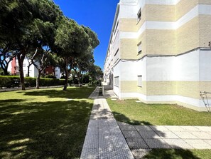 Ein Weg führt zu einem Gebäude mit moderner Architektur, umgeben von gepflegtem Rasen und Bäumen.