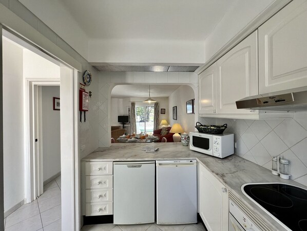 A modern kitchen with white cabinetry, a built-in microwave, a dishwasher, and a black stovetop.