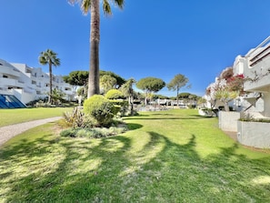 A well-maintained garden with palm trees and manicured lawns, surrounded by modern buildings with balconies. - Albufeira Balaia Golf Village 2 (Albufeira)