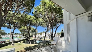 A balcony with a table set for breakfast, overlooking a pool and buildings. - Albufeira Balaia Golf Village 2 (Albufeira)