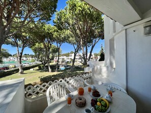 A balcony with a table set for breakfast, overlooking a pool and buildings. - Albufeira Balaia Golf Village 2 (Albufeira)