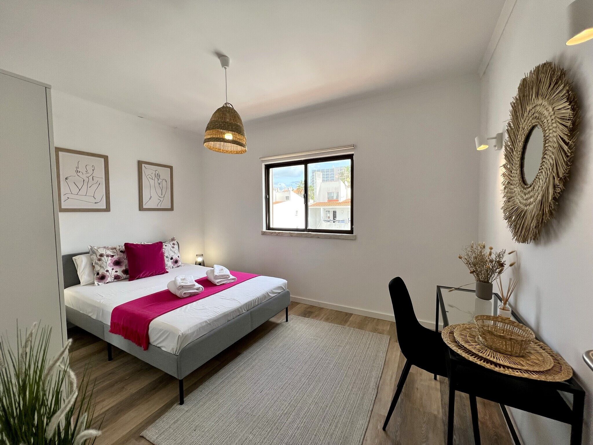 A modern bedroom with a bed, a window, a chair, and a decorative mirror.