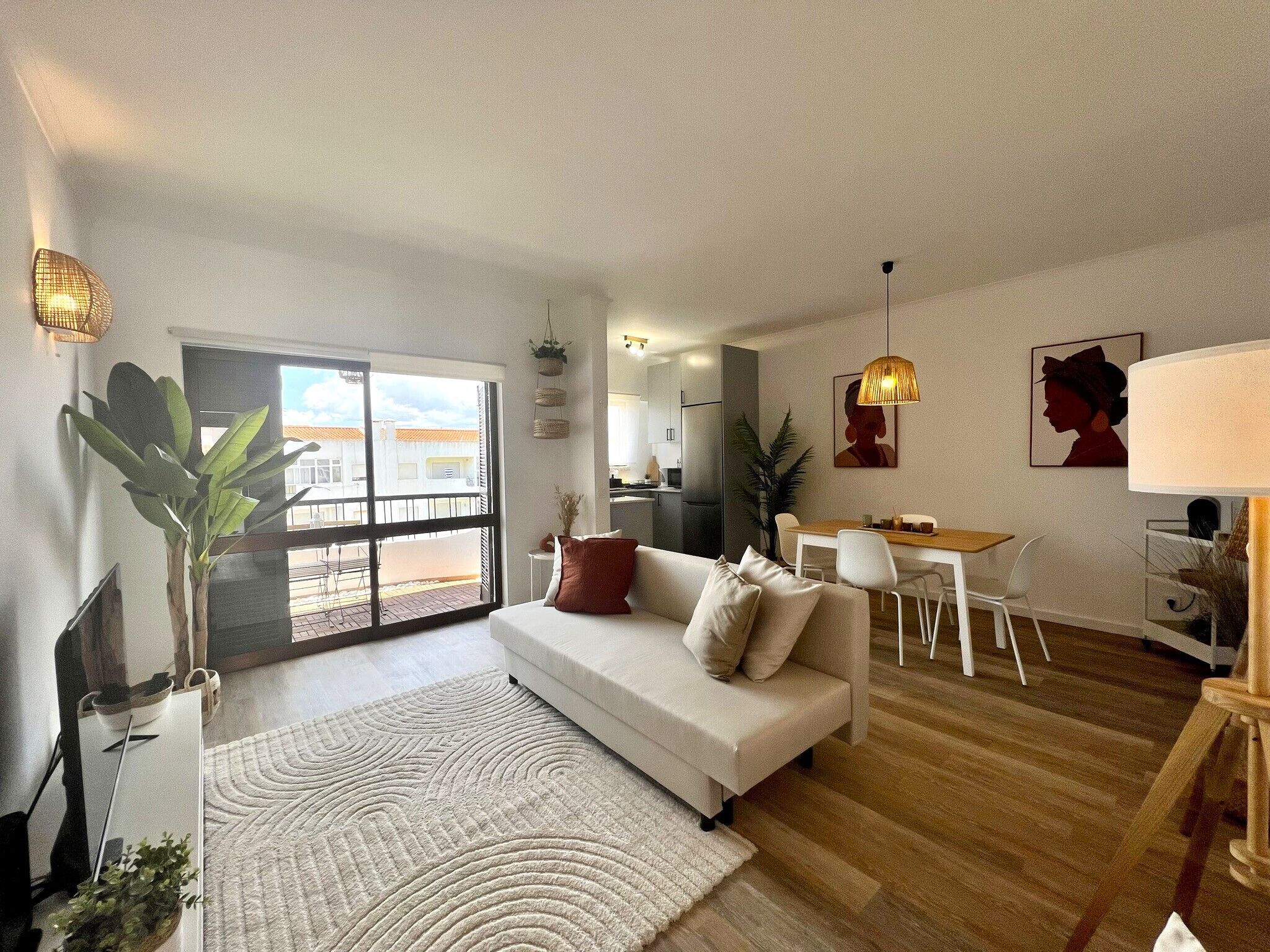 Un salon moderne avec un canapé, une table à manger et des chaises. Une grande fenêtre offre une vue sur l’extérieur.