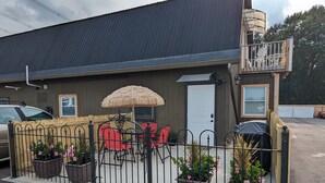 A building with a fenced patio area, outdoor seating, and potted plants. - The Calico Cottage - Fire Pit - Hot Tub (Lewis Center)