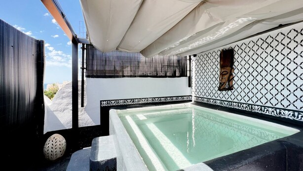 A rooftop pool with a geometric tile design, a white and black color scheme, and a view of the cityscape.