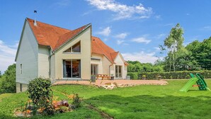 A two-story house with a sloped roof, a front porch, and a backyard with a playset.