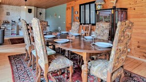 A wooden dining room with a round table set for six, surrounded by patterned upholstered chairs.