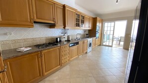 A kitchen with wooden cabinets, a gas stove, a washing machine, and a tiled floor. - Pêra Amazing Villa With Pool by Homing (Silves)