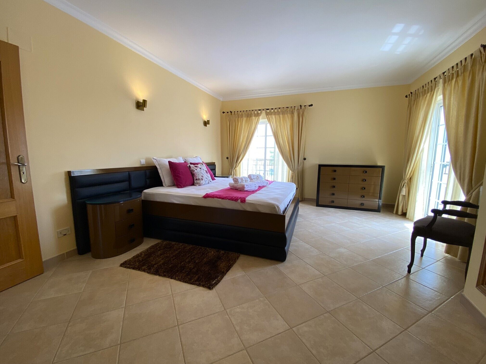 A bedroom with a bed, bedside tables, a dresser, and a chair.