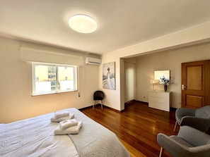 Ein Hotelzimmer mit Bett, Schreibtisch, Stuhl, Fenster und Tür.